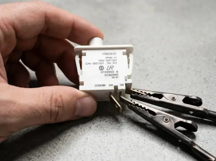 Technician testing LG dryer door switch with multimeter